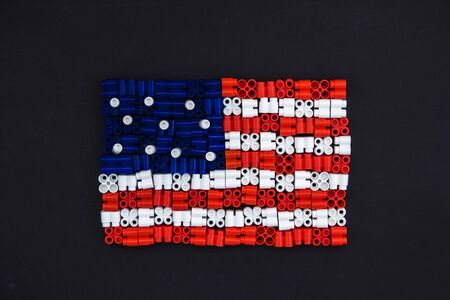 Colorful plastic bricks which form the US flag on black paper background. Parts of bright small spare parts for toys. Top viewの写真素材