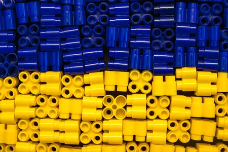 Plastic bricks are yellow and blue on a black background. Details of toys. Top viewの写真素材