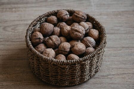 Walnuts in a round wicker basket on a wooden background. Top viewの写真素材