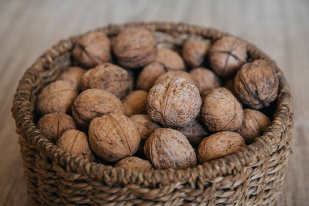 Walnuts in a round wicker basket on a wooden background. Close up
