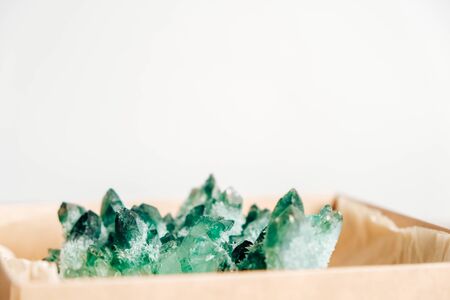 Raw emerald and gemstone rough rock crystal in a kraft paper box on wooden background. Copy, empty space for text.の写真素材