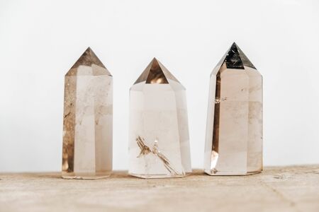 Three smoky natural quartz crystals on a wooden surface on a white background. Copy, empty space for text.の写真素材