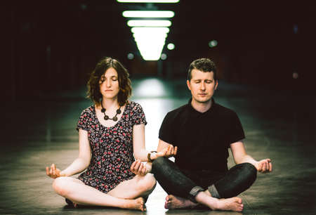 Young couple meditating together sitting in the parking lotの写真素材