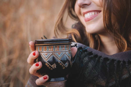 Beautiful girl smiles and holds a cup with a drink. Focusing on the cupの写真素材