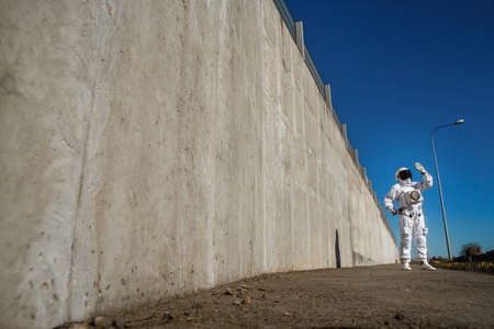 Futuristic astronaut in a helmet against gray walls. Fantastic Cosmic Costume.の写真素材