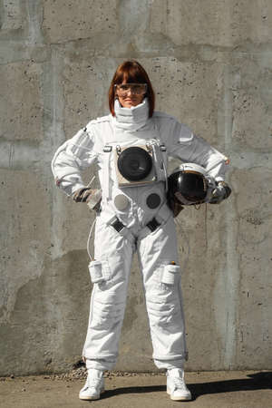 Beautiful girl astronaut without a helmet on the background of a gray wall. Fantastic space suit.の写真素材