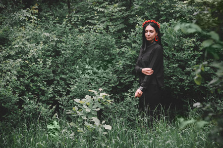 Beautiful girl with her eyes closed in black clothes and red earrings on the background of the...