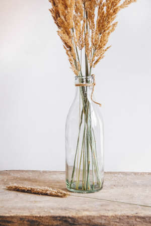 Still life of a bouquet of dried flowers in a glass bottle on a wooden table. Place for text or advertisingの写真素材
