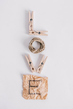Inscription word love made of wooden clothespins, rope and brown paper sticker on white background....