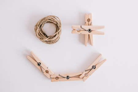 Wooden clothespins with rope on white background which are composed in the form of a smile icon. View from above. Place for your textの写真素材