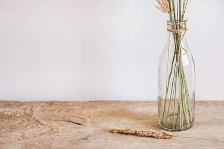 Still life of a bouquet of dried flowers in a glass bottle on a wooden table. Place for text or...