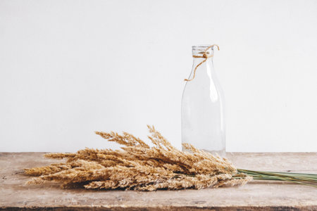 Still life of a bouquet of dried flowers in a glass bottle on a wooden table. Place for text or...