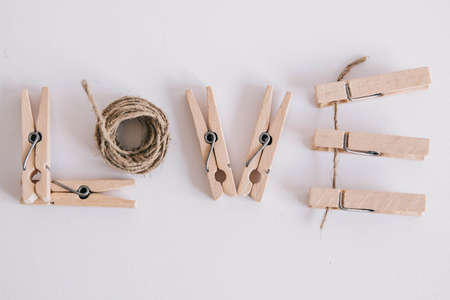Wooden clothespins with rope on white background with the inscription the word love. View from above. Place for your textの写真素材