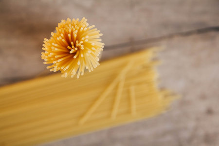 Yellow long spaghetti on an old wooden background. Food concept background. Top view. Copy, empty...