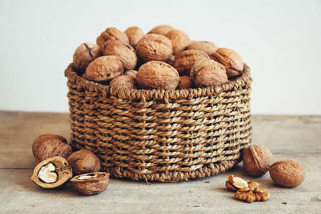 Walnuts in a round wicker basket on a wooden backgroundの写真素材