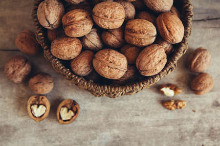 Walnuts in a round wicker basket on a wooden background. Top view. Copy, empty space for textの写真素材