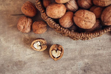 Walnuts in a round wicker basket on a wooden background. Top view. Copy, empty space for textの写真素材