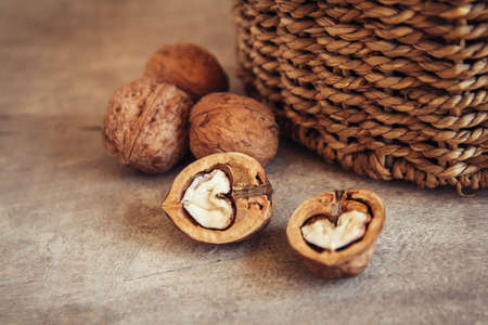 Walnuts in a round wicker basket on a wooden background. Place for your textの写真素材