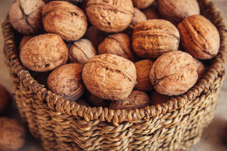 Walnuts in a round wicker basket on a wooden background. Place for your textの写真素材