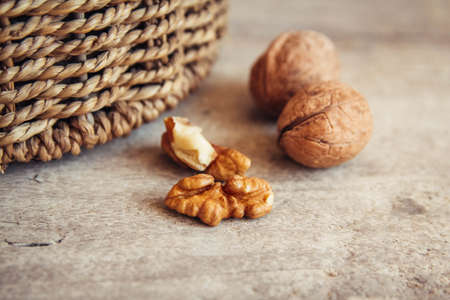 Walnuts in a round wicker basket on a wooden background. Place for your text.の写真素材