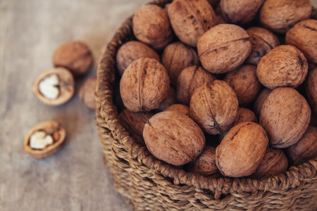 Walnuts in a round wicker basket on a wooden background. Place for your text.の写真素材