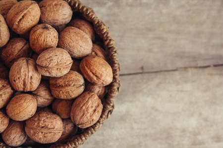 Walnuts in a round wicker basket on a wooden background. Top view. Copy, empty space for textの写真素材