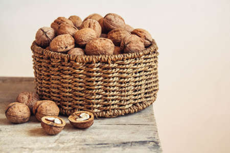 Walnuts in a round wicker basket on a wooden background. Place for your textの写真素材