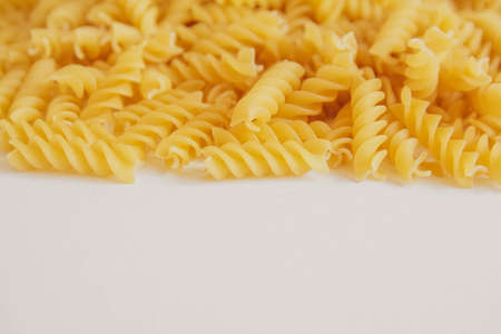 Spiral pasta on a white background. Closeup of raw helix-shape fusilli macaroni on white background. Copy, empty space for text.の写真素材