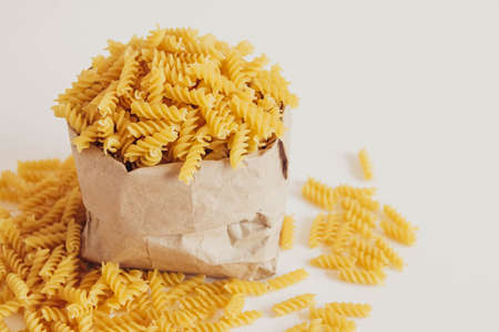 plenty of raw pasta in paper bag on white background. Copy, empty space for text.の写真素材