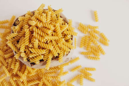 plenty of raw pasta in paper bag on white background. Top view. Copy, empty space for text.の写真素材