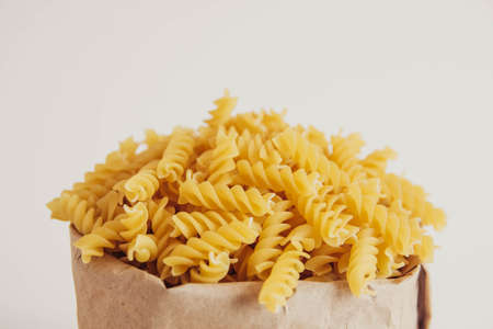 plenty of raw pasta in paper bag on white background. Copy, empty space for text.の写真素材