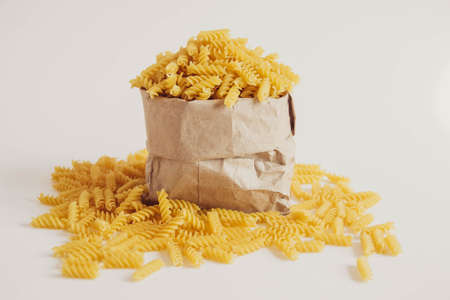 plenty of raw pasta in paper bag on white background. Copy, empty space for text.の写真素材