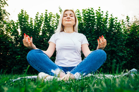 Beautiful blonde girl in headphones and smartphone in hands listens to music lying on green background. Lifestyle concept. Copy, empty space for text.の写真素材