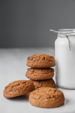 Milk in a glass jar and oatmeal cookies on a white table background. Copy, empty space for textの写真素材