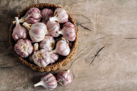 Garlic in a wicker basket on a wooden table background. Copy, empty space for text.の写真素材