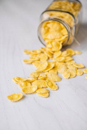 Corn flakes in a glass jar on white wooden surface. Place for your text.の写真素材