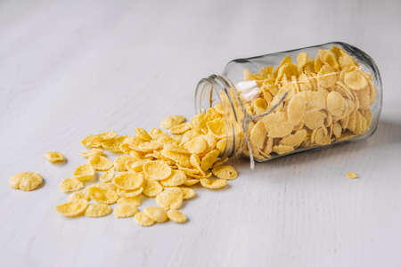 Corn flakes in a glass jar on white wooden surface. Place for your text.の写真素材