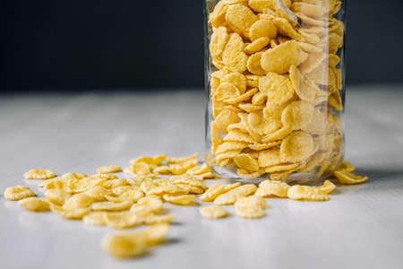 Corn flakes in a glass jar on white wooden surface. Place for your text.の写真素材