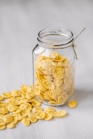 Corn flakes in a glass jar on white wooden surface. Place for your text.