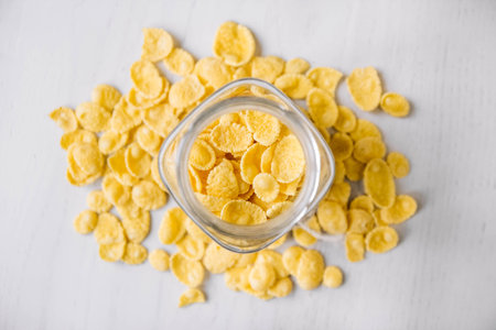 Corn flakes in a glass jar on white wooden surface. Top view. Place for your text.