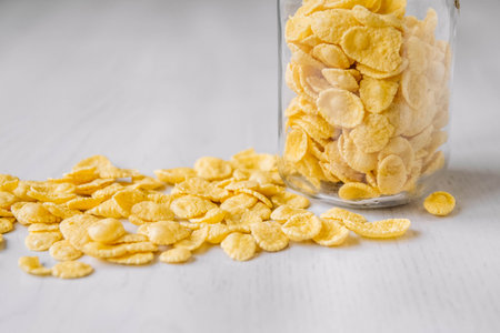Corn flakes in a glass jar on white wooden surface. Top view. Place for your text.