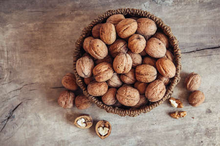 Walnuts in a round wicker basket on a wooden background. Place for your text.の写真素材