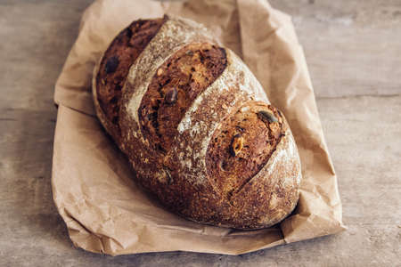Brown fresh bread with seeds are cut into pieces on old wood background. Top view, copy space.の写真素材