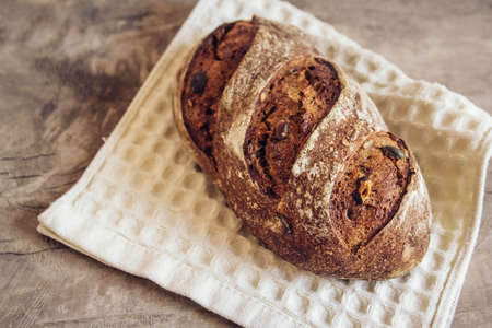 Brown fresh bread with seeds are cut into pieces on old wood background. Top view, copy space.の写真素材