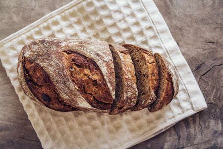 Brown fresh bread with seeds are cut into pieces on old wood background. Copy, empty space for text.の写真素材
