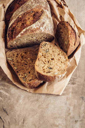 Brown fresh bread with seeds are cut into pieces on old wood background. Copy, empty space for text.の写真素材