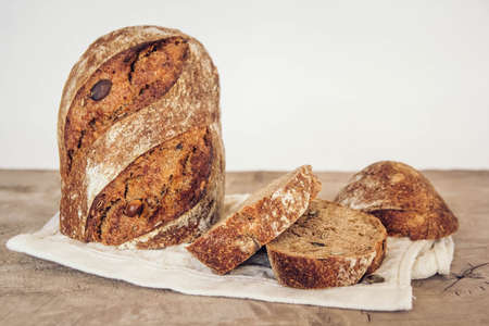 Brown fresh bread with seeds are cut into pieces on old wood background. Top view, copy space.の写真素材