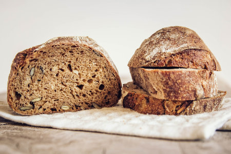 Brown fresh bread with seeds are cut into pieces on old wood background. Top view, copy space.の写真素材