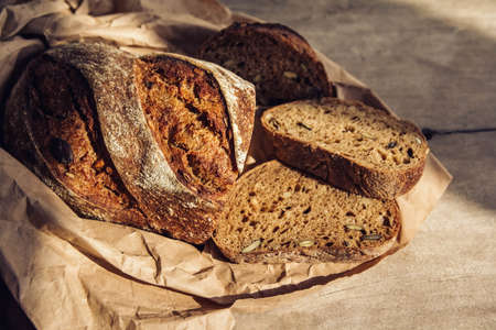 Brown fresh bread with seeds are cut into pieces on old wood background. Top view, copy space.の写真素材
