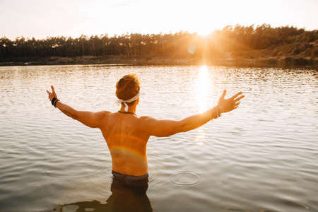 Man lying on wooden bridge against the background of the water in which the sky is reflected flinging his hands to the side. Concept of freedom relaxation. Place for text or advertising.の写真素材